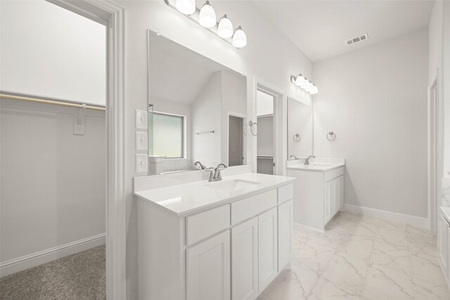 bathroom featuring two vanities, baseboards, marble finish floor, and a sink