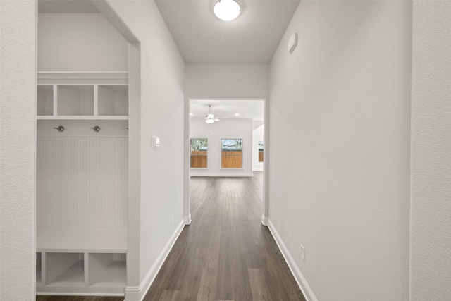 corridor with baseboards and dark wood-style flooring