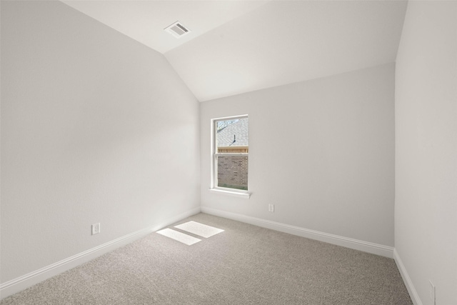 empty room featuring visible vents, baseboards, carpet, and lofted ceiling