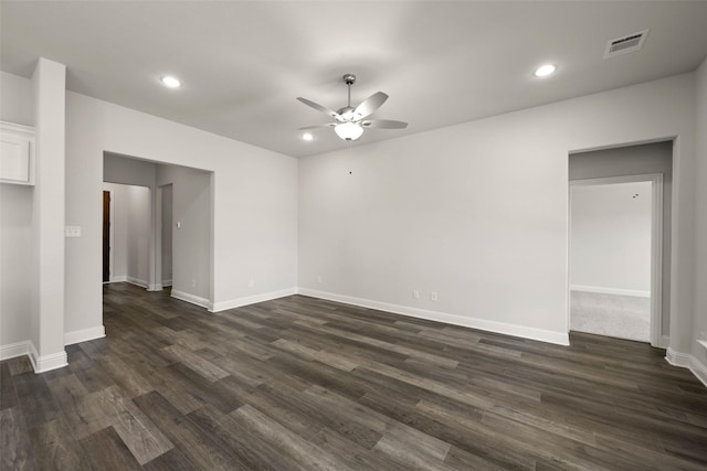 spare room featuring ceiling fan, visible vents, baseboards, and dark wood finished floors