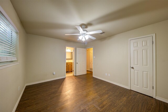 unfurnished bedroom featuring ensuite bath, dark wood-type flooring, and ceiling fan