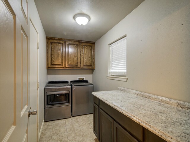 washroom featuring washing machine and clothes dryer, cabinets, light tile patterned floors, and a textured ceiling