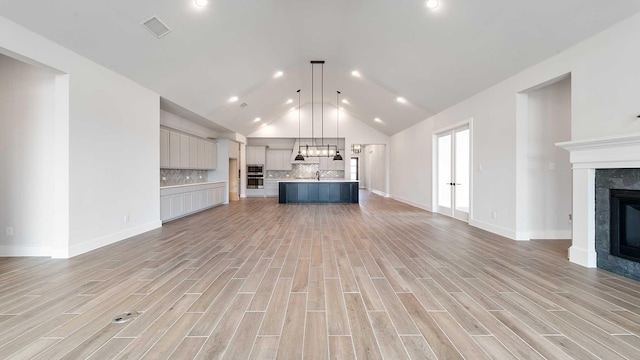 unfurnished living room featuring a high end fireplace, visible vents, baseboards, and light wood-style floors