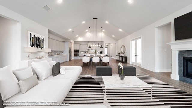 living room featuring visible vents, wood finished floors, baseboards, and a premium fireplace