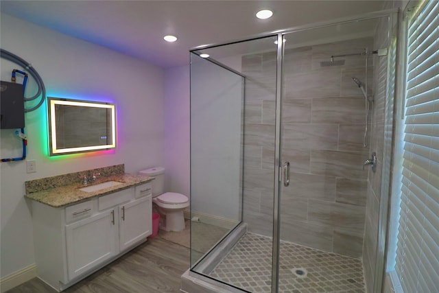 bathroom featuring vanity, toilet, hardwood / wood-style flooring, and a shower with shower door