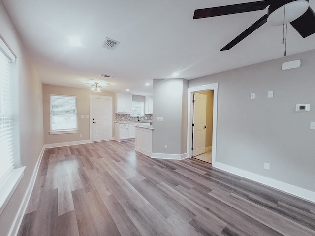 unfurnished living room featuring sink, ceiling fan, and light hardwood / wood-style floors