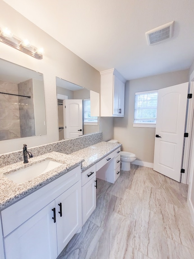 bathroom with vanity, toilet, and a tile shower