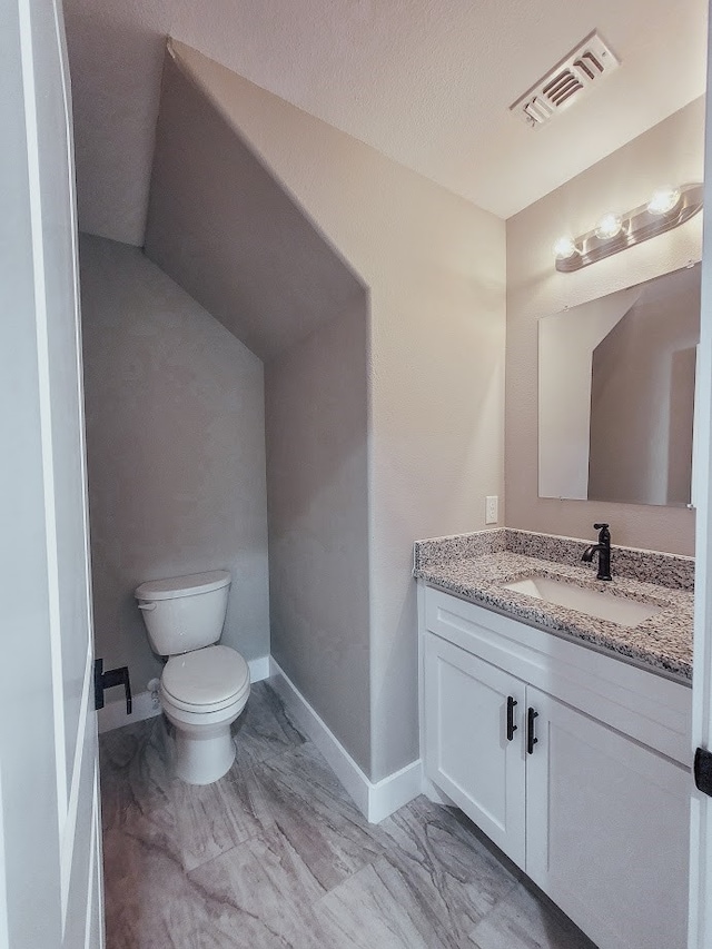 bathroom featuring toilet, a textured ceiling, and vanity