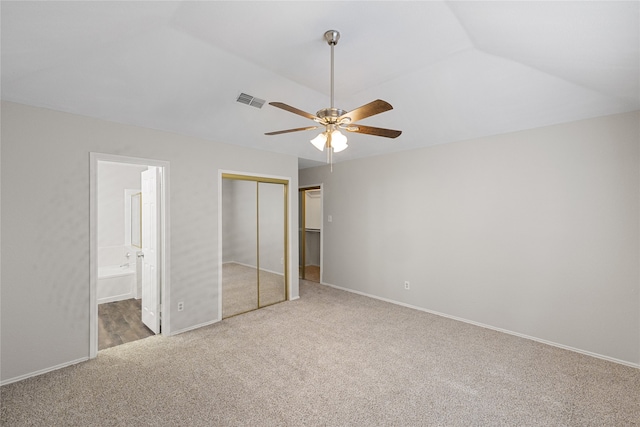 unfurnished bedroom with ceiling fan, vaulted ceiling, light carpet, and ensuite bath