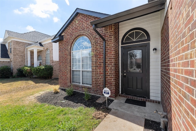 view of exterior entry featuring a lawn