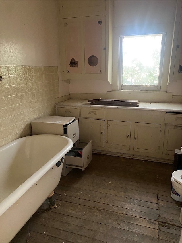 bathroom with toilet, tile walls, hardwood / wood-style floors, and a washtub