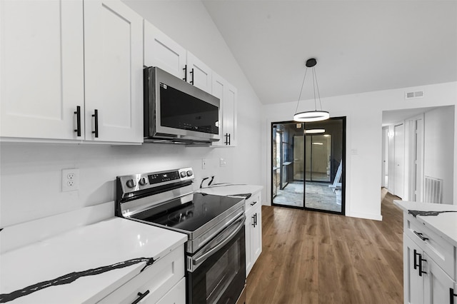 kitchen with vaulted ceiling, pendant lighting, wood-type flooring, appliances with stainless steel finishes, and white cabinetry