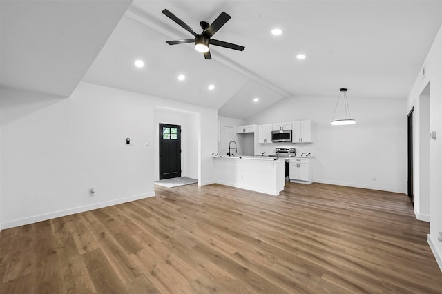 unfurnished living room featuring hardwood / wood-style floors, ceiling fan, sink, and vaulted ceiling with beams