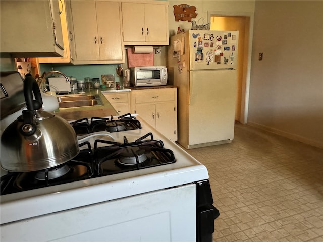 kitchen with cream cabinets, sink, and white appliances