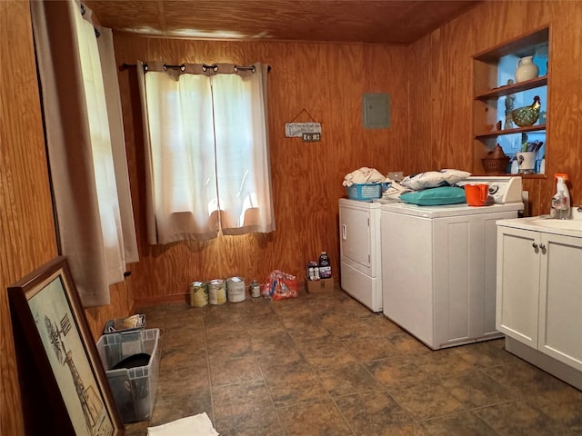 washroom featuring wood walls, cabinets, and washer and clothes dryer