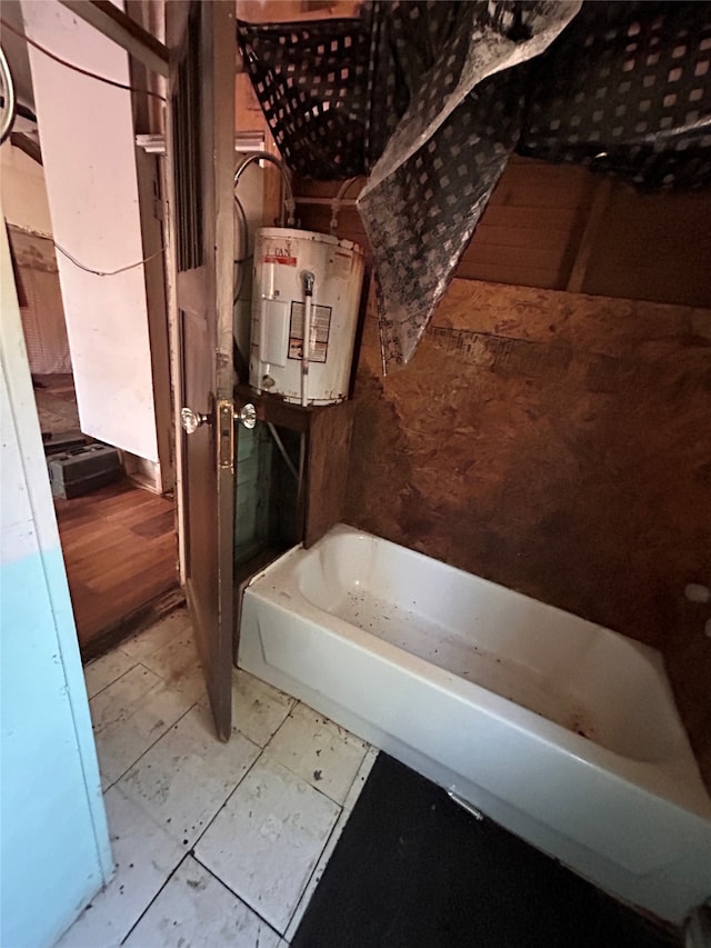 bathroom featuring tile patterned flooring, a bathtub, and water heater