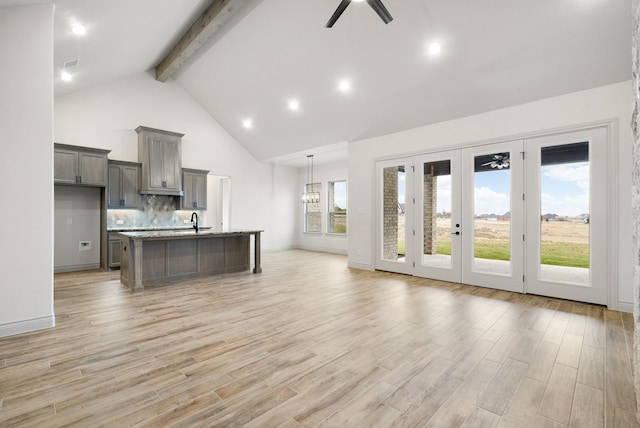 kitchen with ceiling fan with notable chandelier, light wood-type flooring, a kitchen island with sink, and a healthy amount of sunlight