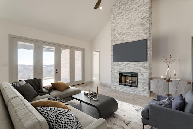 living room featuring ceiling fan, french doors, high vaulted ceiling, light hardwood / wood-style floors, and a fireplace