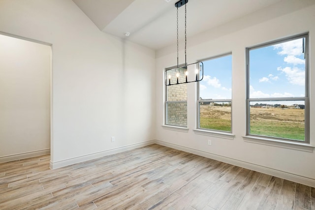 unfurnished dining area featuring a chandelier, light wood-type flooring, and plenty of natural light