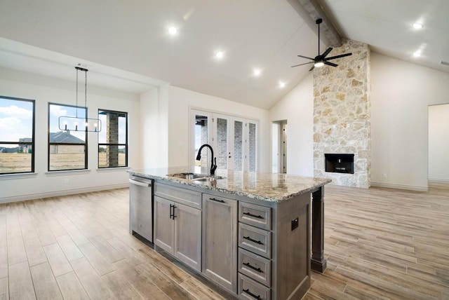 kitchen with light hardwood / wood-style floors, stainless steel dishwasher, hanging light fixtures, and sink