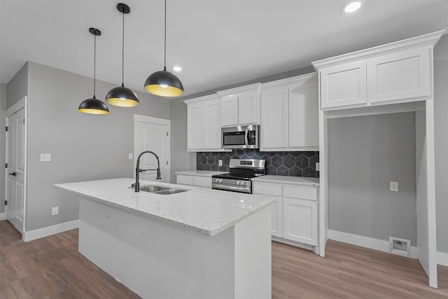 kitchen featuring light wood-type flooring, sink, an island with sink, appliances with stainless steel finishes, and white cabinets