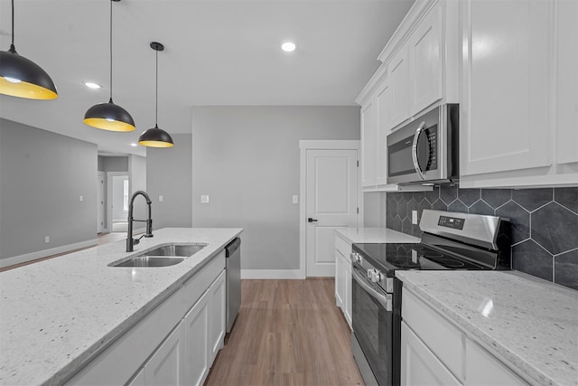 kitchen featuring pendant lighting, white cabinetry, light hardwood / wood-style flooring, stainless steel appliances, and sink