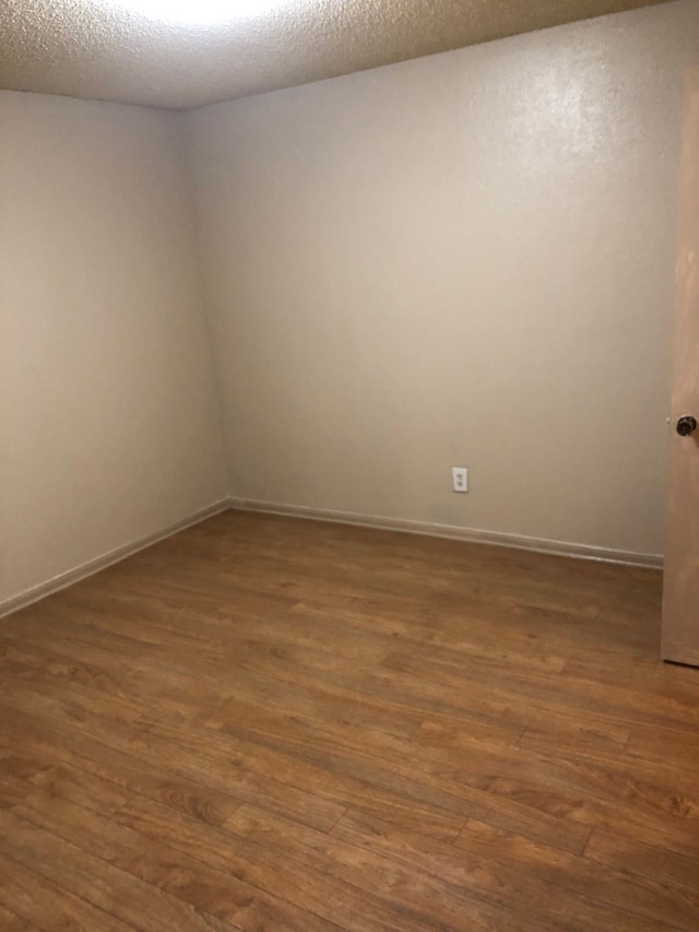 empty room featuring a textured ceiling and dark wood-type flooring