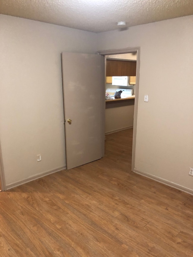 unfurnished room featuring a textured ceiling and light wood-type flooring