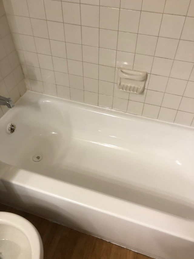 bathroom with toilet, wood-type flooring, and a tub