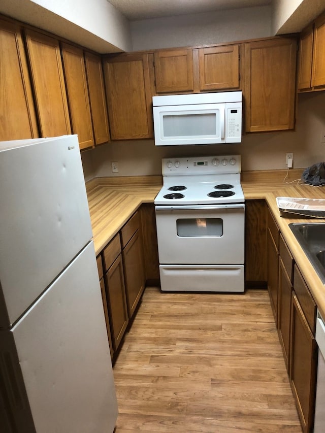 kitchen with light wood-type flooring and white appliances