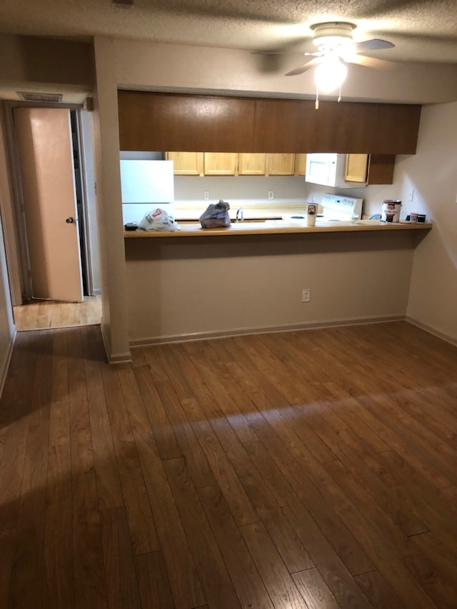 kitchen featuring a textured ceiling, white appliances, light brown cabinetry, dark wood-type flooring, and ceiling fan