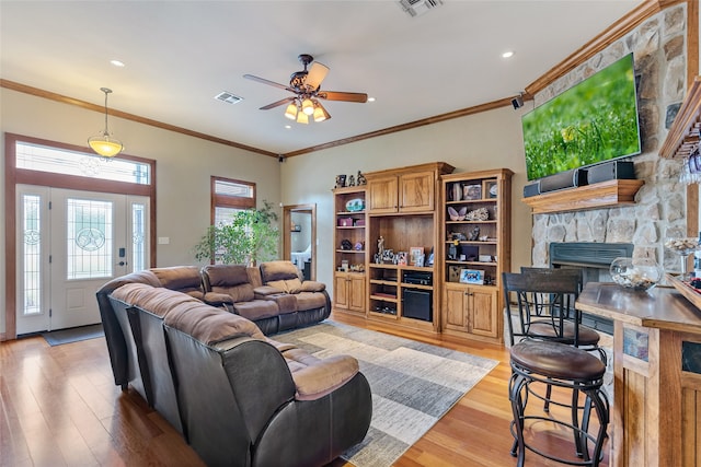 living room featuring a wealth of natural light, light hardwood / wood-style floors, ceiling fan, and a fireplace