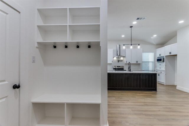 mudroom featuring light wood-type flooring, lofted ceiling, and sink