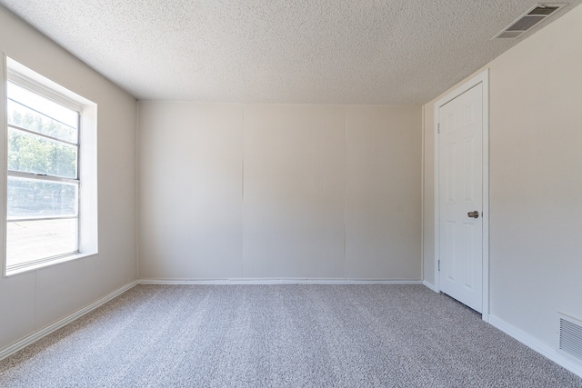 unfurnished room featuring plenty of natural light, carpet, and a textured ceiling