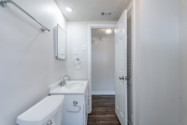 bathroom with a textured ceiling, vanity, toilet, and hardwood / wood-style flooring