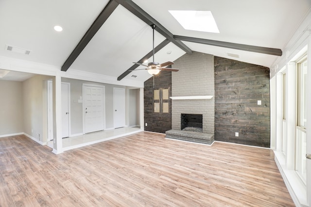 unfurnished living room featuring light hardwood / wood-style floors, lofted ceiling with skylight, a wealth of natural light, and ceiling fan