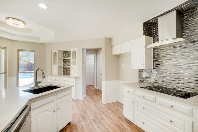 kitchen featuring wall chimney exhaust hood, black gas stovetop, sink, and white cabinets