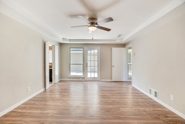 unfurnished room with ceiling fan, a raised ceiling, and light wood-type flooring