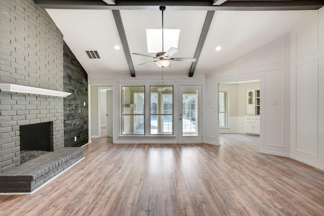 unfurnished living room featuring hardwood / wood-style flooring, ceiling fan, a fireplace, and vaulted ceiling with beams