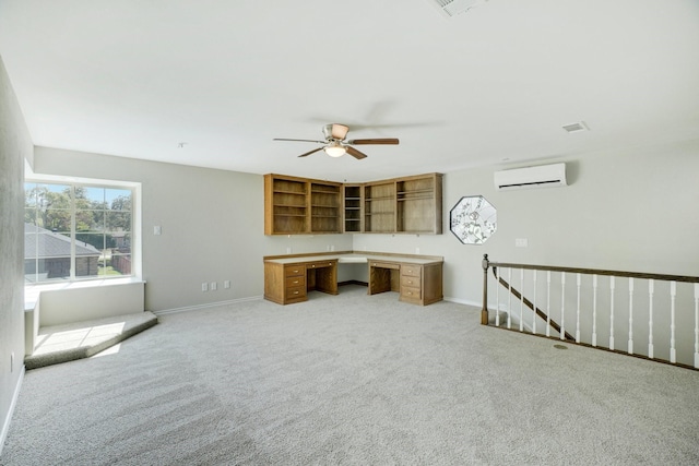 office featuring ceiling fan, light colored carpet, built in desk, and an AC wall unit