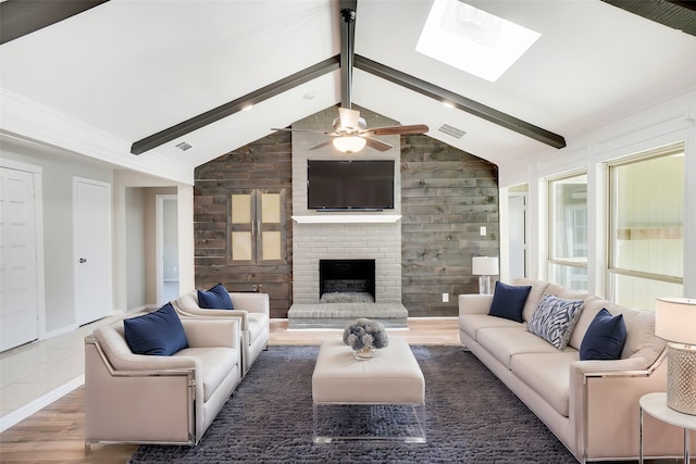 living room with dark wood-type flooring, wooden walls, vaulted ceiling with skylight, ceiling fan, and a fireplace