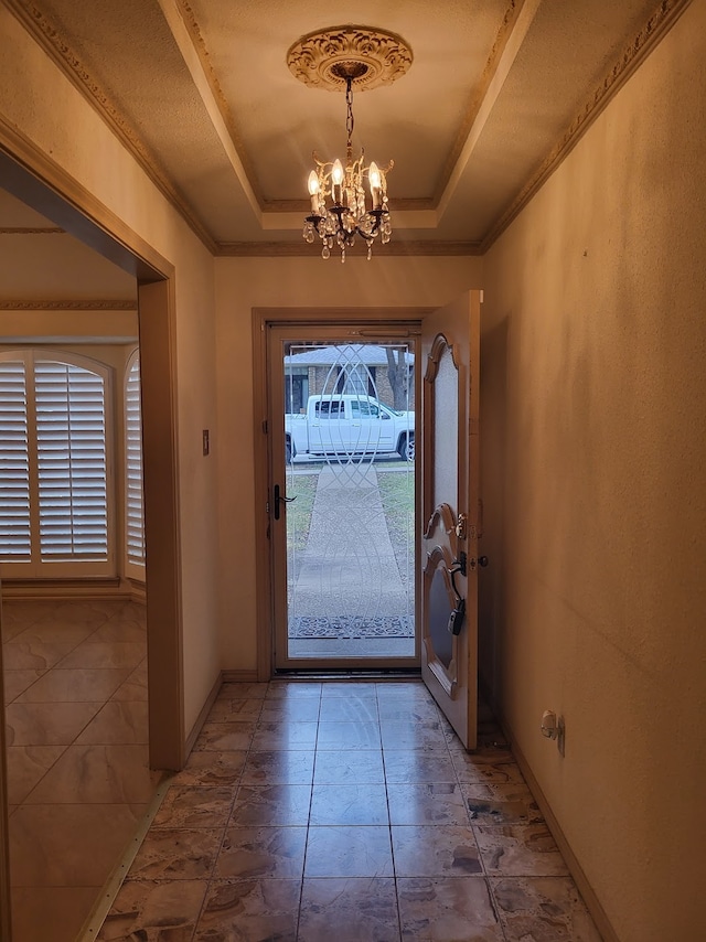 entrance foyer with a notable chandelier, a raised ceiling, and a healthy amount of sunlight