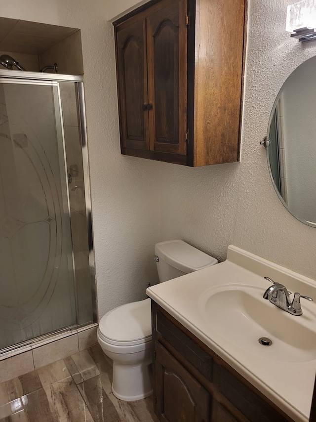 bathroom with walk in shower, vanity, and toilet