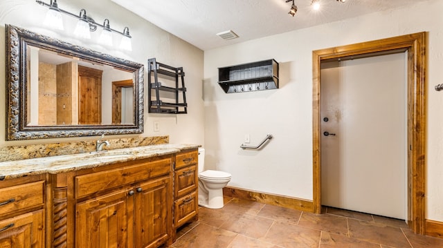 bathroom featuring vanity, toilet, and a textured ceiling