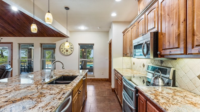 kitchen featuring decorative light fixtures, light stone countertops, plenty of natural light, stainless steel appliances, and sink