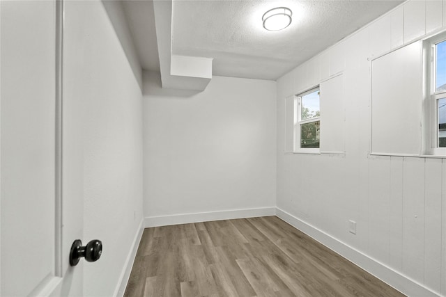 spare room with a textured ceiling and light hardwood / wood-style floors