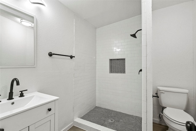 bathroom featuring vanity, toilet, and a tile shower