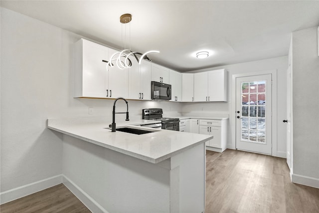 kitchen featuring range, pendant lighting, light hardwood / wood-style flooring, sink, and white cabinets