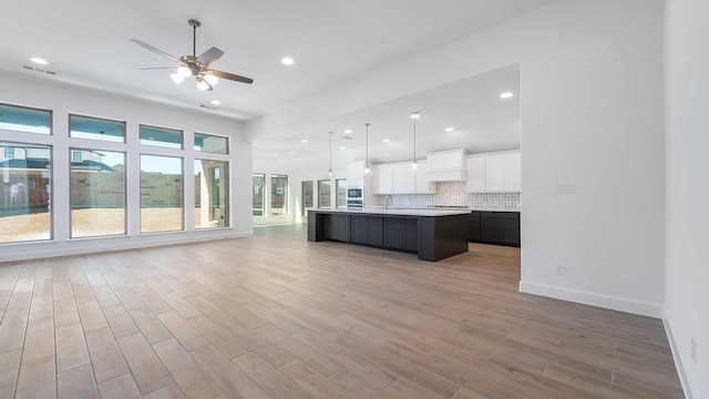 kitchen featuring a ceiling fan, a sink, open floor plan, light wood finished floors, and light countertops