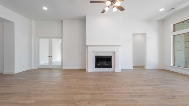 unfurnished living room featuring visible vents, ceiling fan, a premium fireplace, recessed lighting, and light wood-style flooring